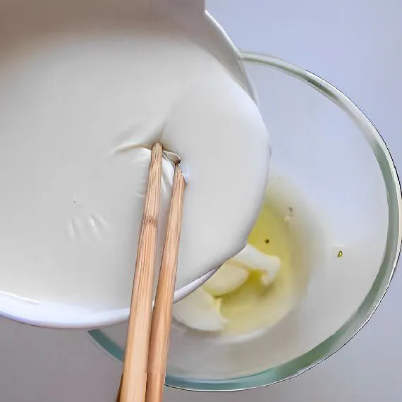 Di wadah terpisah, siapkan 2 butir putih telur. Dengan menggunakan sumpit atau sendok, tekan perlahan lapisan kulit susu agar susu di bawahnya bisa dituangkan ke dalam wadah putih telur
