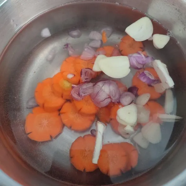 Rebus air, wortel, irisan bawang merah dan bawang putih hingga mendidih dan wortel empuk.