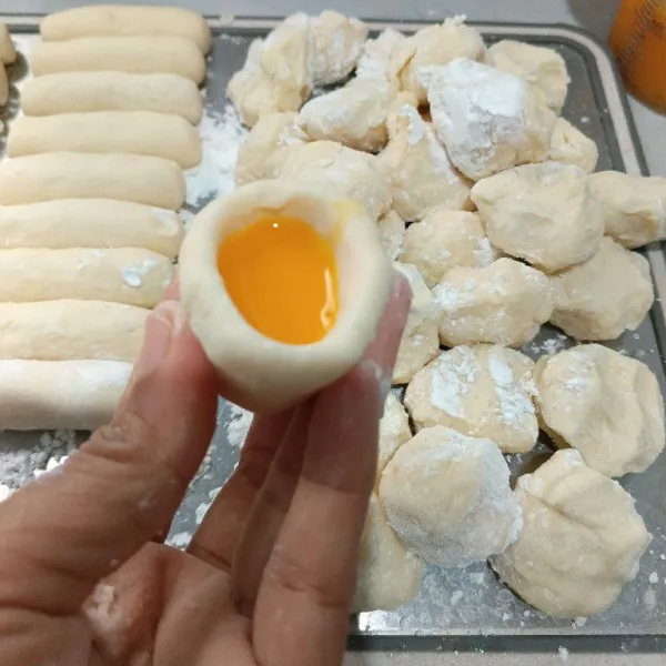 Untuk membuat pempek isian telur, bentuk adonan memanjang, lalu buat cekungan, kemudian tuang setengah telur. Rapatkan tepi atasnya.