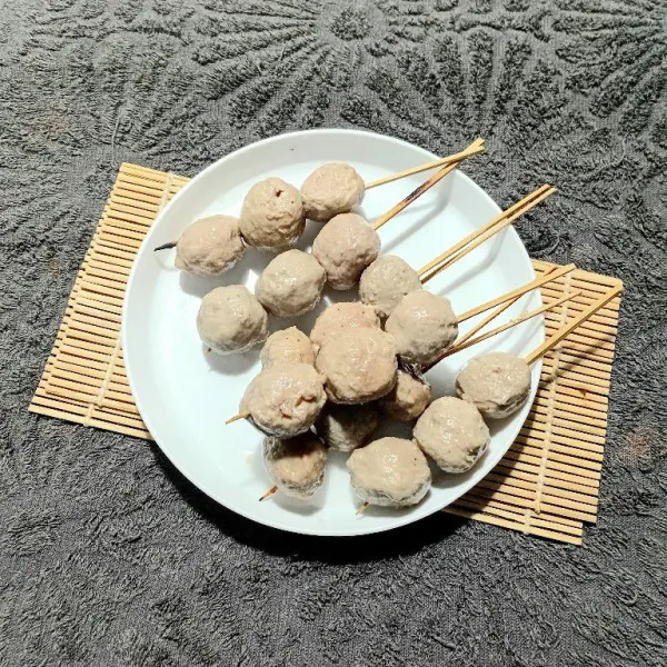 Tusuk bakso sapi menjadi tiga bagian dengan tusukan sate.