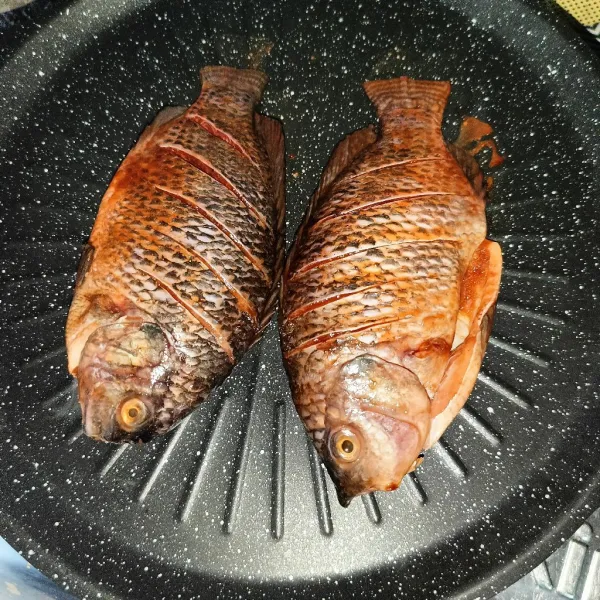 Panaskan alat pemanggang dan taruh ikan di atasnya. Bakar ikan dengan api kecil saja.