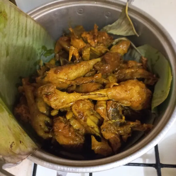 Alasi kukusan dengan daun pisang, tuang ayam ke dalamnya tutup kembali dengan daun pisang, lqlu kukus hingga empuk