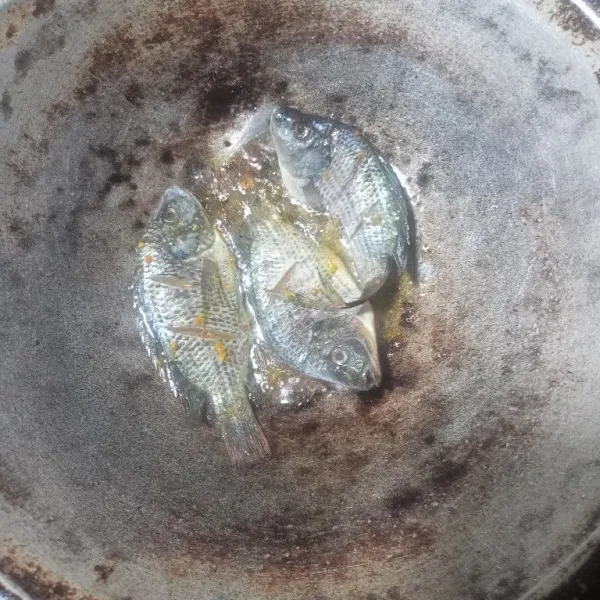 Panaskan minyak, lalu goreng ikan mujair hingga berwarna kuning keemasan.