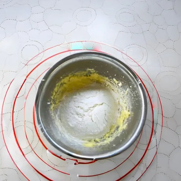 Tambahkan 150 gr tepung terigu protein rendah, lalu aduk hingga adonan menyatu