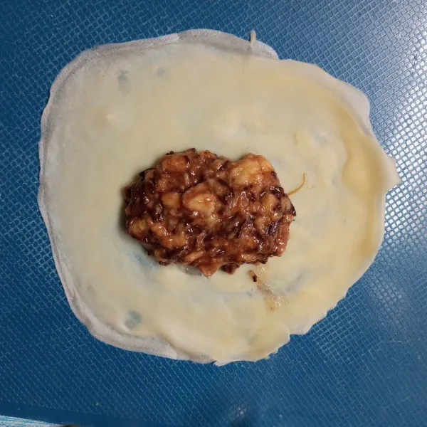 Ambil selembar kulit lumpia, lalu beri isian pisang meses di atasnya.