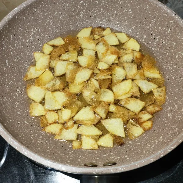Kentang dikupas, diiris tipis, lalu digoreng kering sebagai bahan pelengkap.
