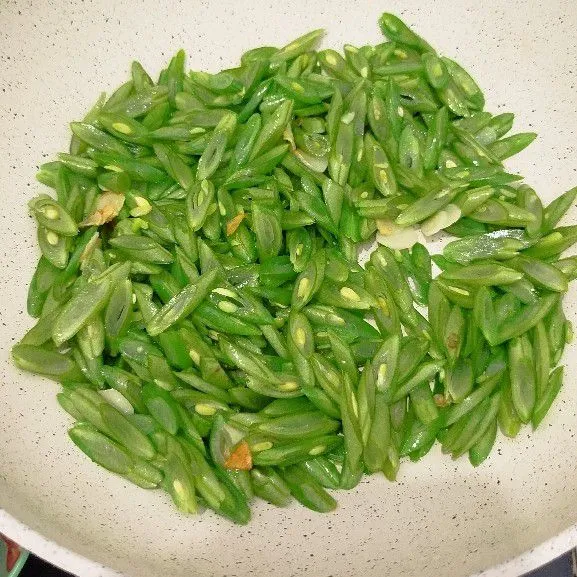 Panaskan minyak goreng dalam pan, tumis bawang putih hingga harum. Tambahkan buncis, masak hingga layu. Tambahkan air, masak hingga buncis setengah sempuk.