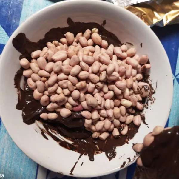 Tuangkan kacang tanah yang sudah disangrai ke dalam lelehan coklat.