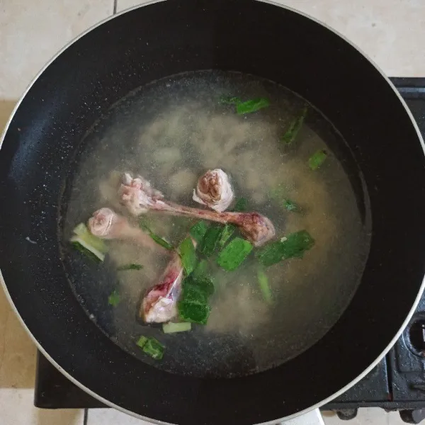 Tambahkan air dan tulang ayam, masak hingga mendidih