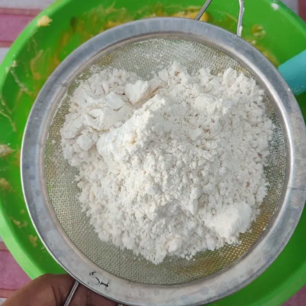 Masukkan tepung terigu dan susu bubuk sambil diayak. Kemudian uleni perlahan dengan tangan sampai membentuk adonan.