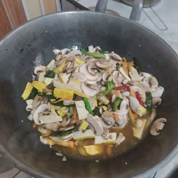 Lalu masukkan semua jamur, tahu, wortel, dan brokoli. Tambahkan air, gula, dan garam, masak hingga matang.