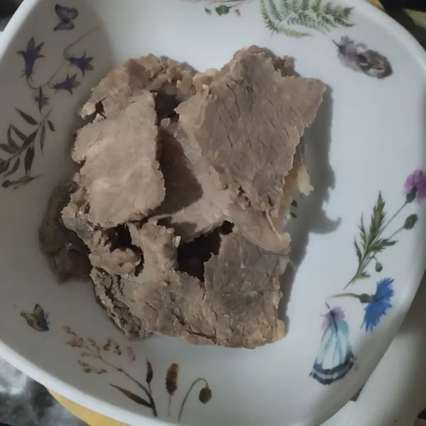 Iris lebar daging yang sudah direbus lalu sedikit pipihkan menggunakan ulekan.