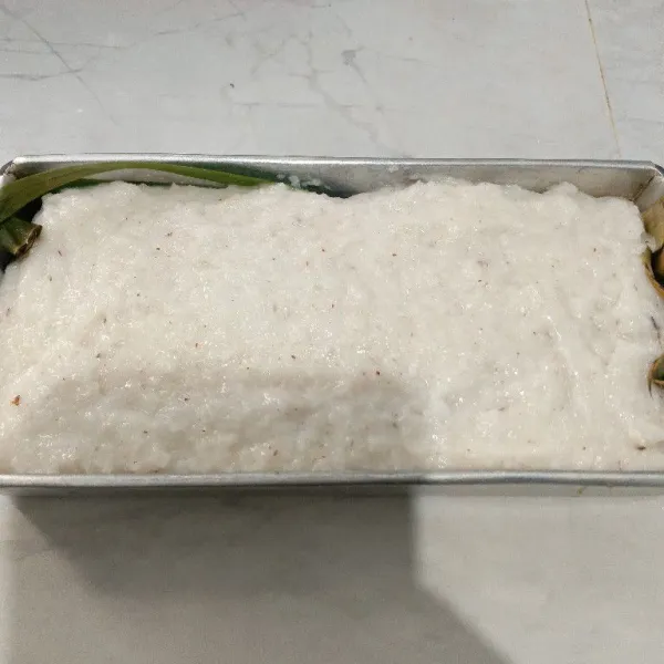 Masukkan adonan ketan ke dalam loyang yang sudah di alasi dengan daun pisang.
