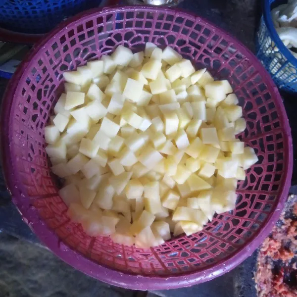 Iris kotak-kotak kentang dan cuci bersih. Lalu, tiriskan kentang.