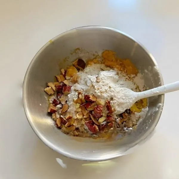 Tambahkan 2 butir telur, 5 gr baking powder, 60 gr tepung oat, 20 gr kurma merah kering cincang, dan 15 gr kacang walnut. Aduk rata