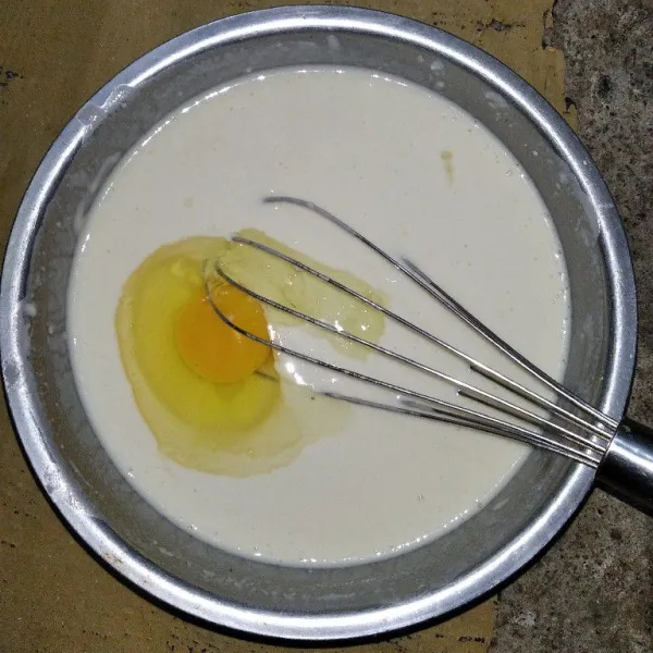 Kemudian tambahkan air sedikit demi sedikit sambil di aduk agar tidak bergerindil, setelah itu tambahkan telur, aduk hingga rata