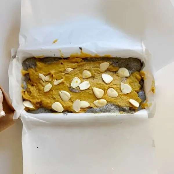 Tuang sisa adonan labu di atasnya, ratakan permukaan. Hias dengan irisan almond. Panggang dalam oven yang sudah dipanaskan pada suhu 170°C selama 35 menit