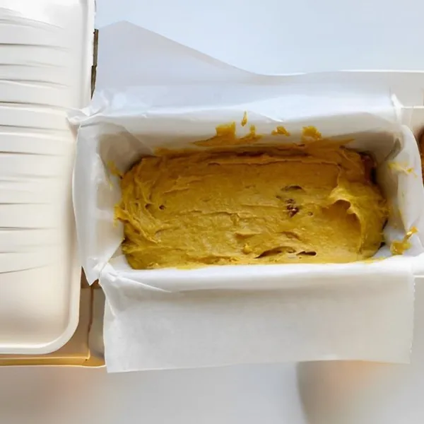 Siapkan loyang berukuran 20 cm, alasi dengan kertas roti. Tuang setengah adonan ke dalam loyang