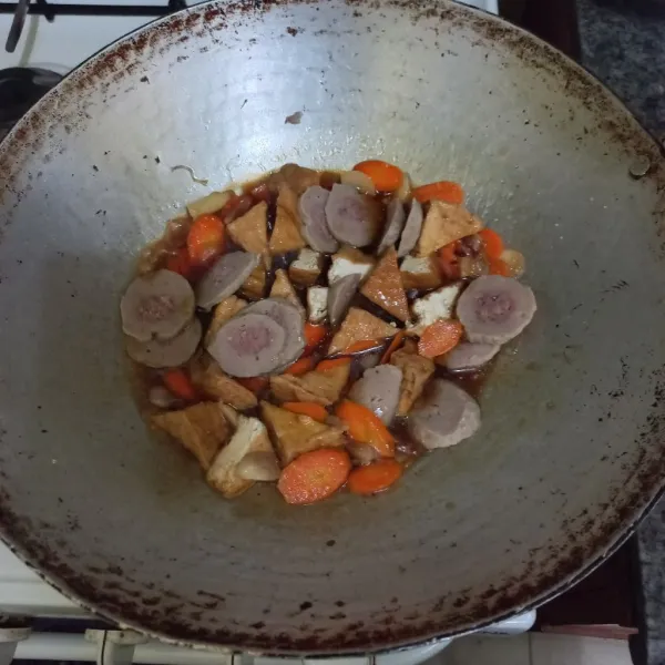Masukkan potongan tahu cokelat, kemudian tuang irisan bakso sapi.