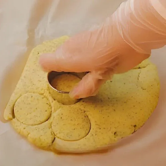 Giling adonan menggunakan rolling pin hingga ketebalan sekitar 2 cm. Cetak adonan dengan bentuk bulat kecil. Letakkan di atas loyang yang sudah dialasi kertas panggang