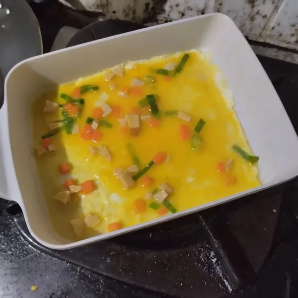 Tuang satu sendok adonan telur di atas wajan datar yang sudah diolesi margarin, ratakan.