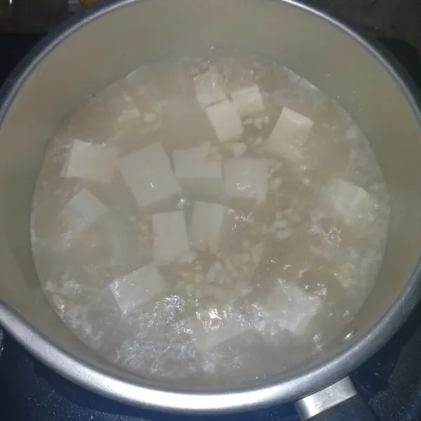 Siapkan air mendidih lalu masukkan tahu dan bawang putih, masak hingga matang.