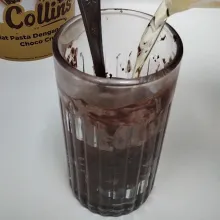 Langkah keempat, siapkan gelas panjang. Isi menggunakan pasta coklat, lalu tuang menggunakan minyak kelapa atau sayur yang sudah dipanaskan. Setelah itu, aduk hingga merata. Untuk pasta coklat, bisa diganti dengan coklat batang atau coklat lainnya sesuai selera.