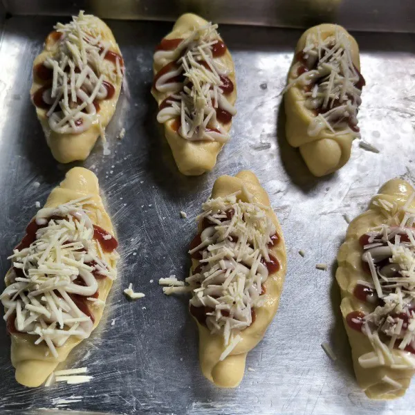 Tambahkan saus tomat dan mayones di atasnya, lalu taburi dengan keju parut diatasnya. Masukkan roti kedalam oven yang sudah dipanaskan terlebih dahulu panggang hingga matang.