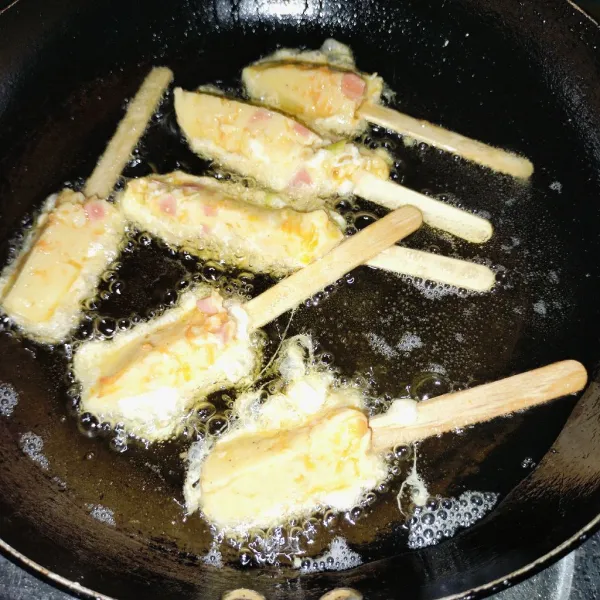 Kemudian bagi empat bagian lalu tusuk dengan tusuk an es cream dan celup kedalam telor goreng hingga matang.