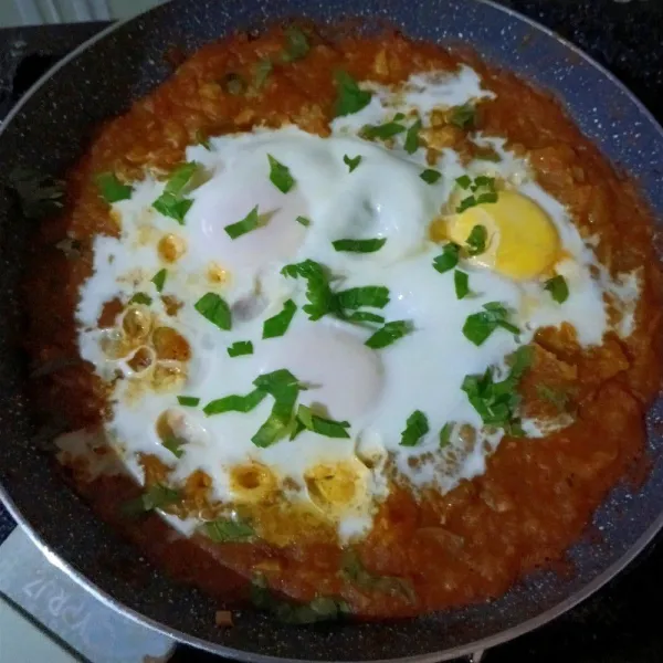 Tutup pan, kecilkan api, masak hingga tingkat kematangan telur sesuai keinginan, lalu tabur dengan seledri / parsley.