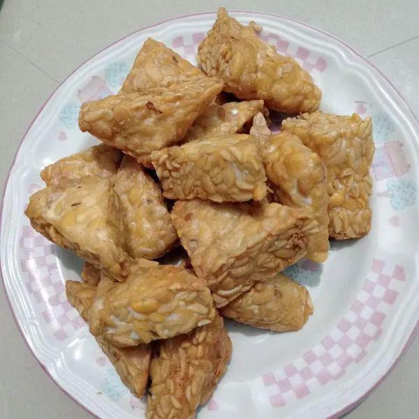 Haluskan bawang putih, ketumbar, garam, kaldu jamur, dan air secukupnya, lalu rendam tempe sebentar dan goreng hingga matang. Angkat dan tiriskan.