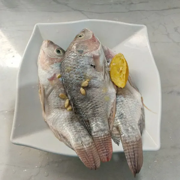 Cuci bersih ikan, lalu baluri dengan air perasan jeruk nipis, tambahkan garam dan merica, aduk rata. Marinasi ikan selama 15-20 menit.