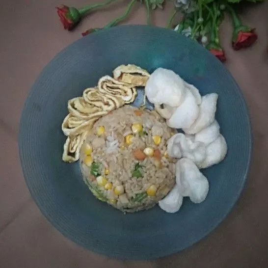 Siapkan piring saji cetak nasi goreng lalu tambahkan irisan telur dadar dan kerupuk.