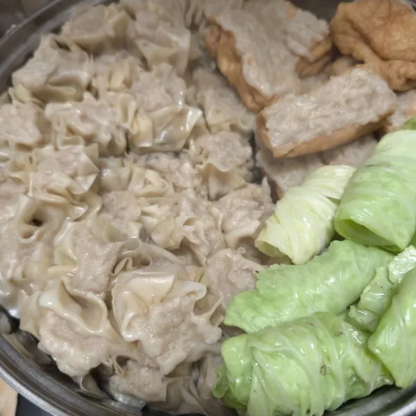 Dipanci terpisah rebus kubis sampai layu, lalu gulung dan tata bersatu siomay dan tahu.