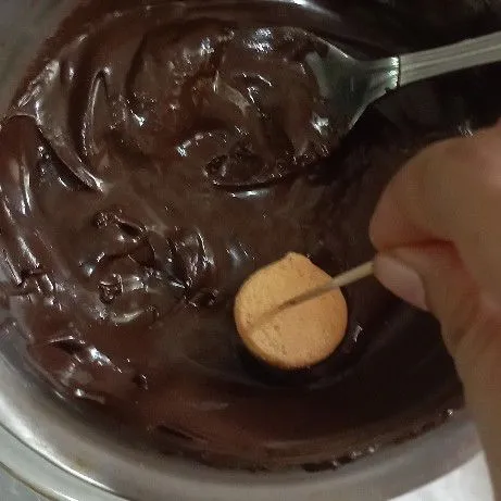 Tusuk bagian belakang eggdrop dengan tusuk gigi, lalu celupkan ke lelehan coklat.