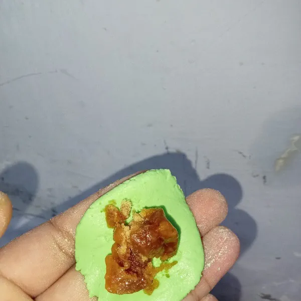 Ambil adonan, lalu pipihkan dan tambahkan gula merah. Bentuk adonan menjadi bulat.