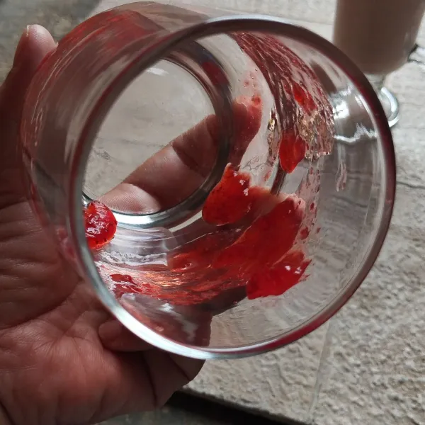 Ambil gelas, kemudian olesi pinggiran gelas dengan selai strawberry. Setelah itu, tuang smoothies yang sudah diblender tadi.
