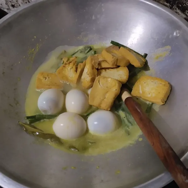 Tambahkan telur dan tahu gorengnya. Masak hingga kacang setengah matang.