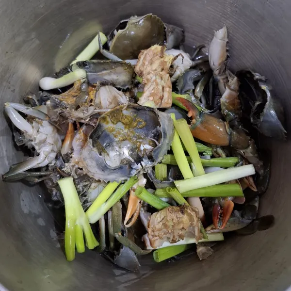 Rebus kepiting di panci/wadah tertutup dengan sedikit air, bawang prei, dan jahe yang telah digeprek, lalu tutup pancinya. Rebus selama kurang lebih 5 menit.