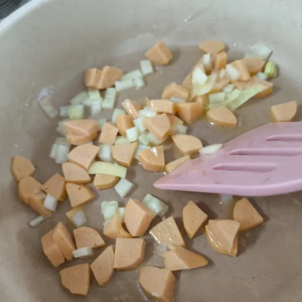 Tumis bawang Bombay dengan margarin hingga harum, kemudian masukkan irisan sosis tumis sebentar.