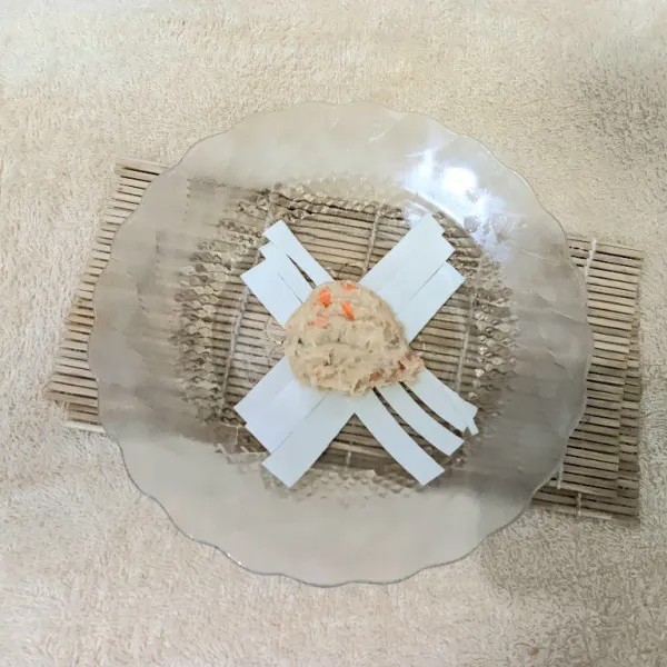 Ambil adonan satu sendok lalu gulingkan ke kulit pangsit yang sudah dipotong memanjang. Lakukan sampai adonan habis.