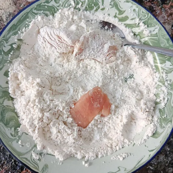 Balur irisan dada ayam dengan tepung pelapis sampai rata.