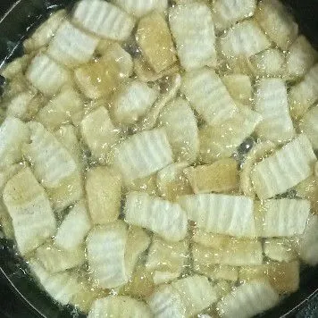 Goreng tahu iris di minyak panas yang agak banyak sampai garing kecoklatan.