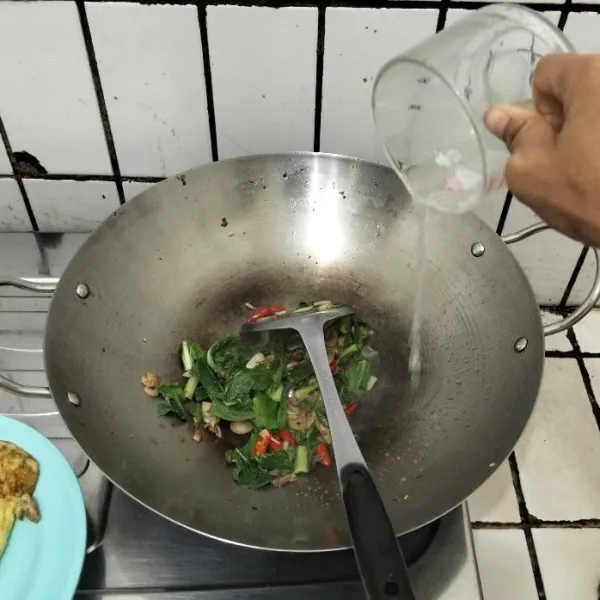 Masukkan caisim, masak sampai layu. Kemudian, tuang air dan tunggu hingga mendidih.