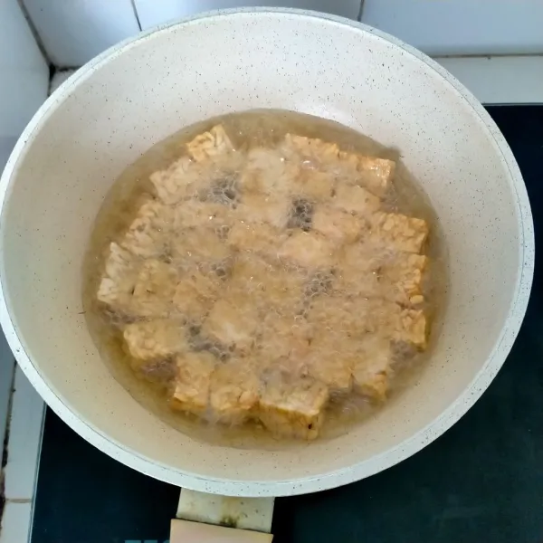 Potong-potong tempe dan goreng hingga tempe berubah warna menjadi agak kecokelatan.