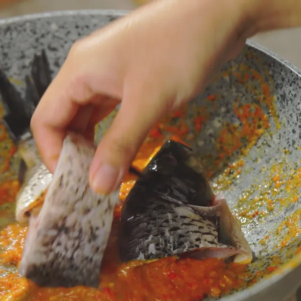 Masukkan ikan ke dalam panci lalu tambahkan air dan daun kemangi, garam, gula, dan kaldu bubuk.