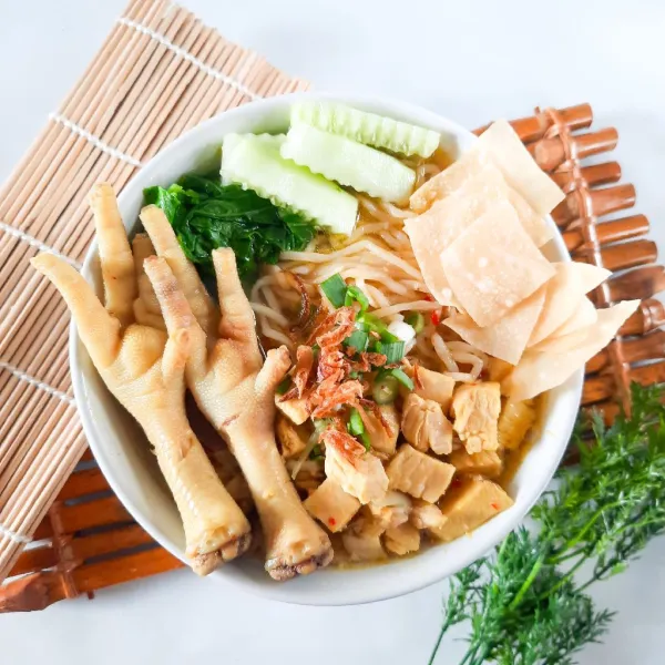 Terakhir, beri toping di atas mie dengan daging ayam, sawi, timun, keripik kulit pangsit, daun bawang, bawang goreng, ceker, dan siram dengan kuah kare. Mie ayam kuah kare siap dinikmati!