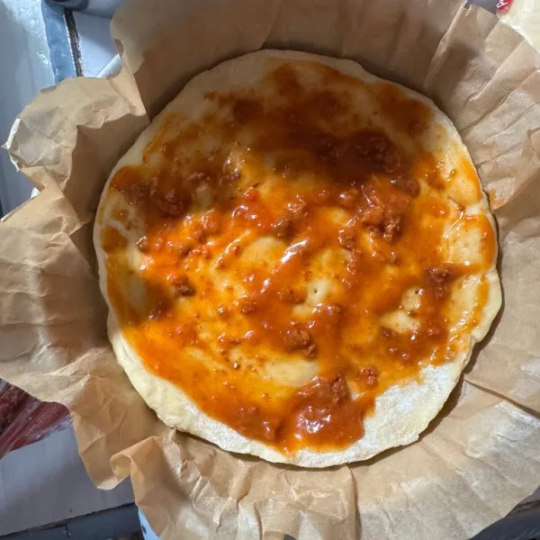 Olesi saus bolognese di atas adonan.