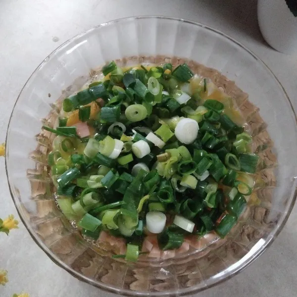 Pecahkan telur. Campurkan potongan sosis dan irisan daun bawang.