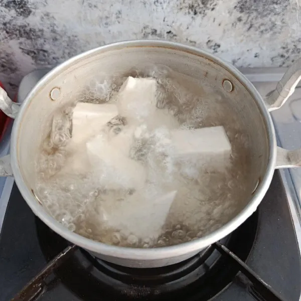 Rebus tahu putih yang sudah dipotong hingga mendidih supaya tidak berasa asam.